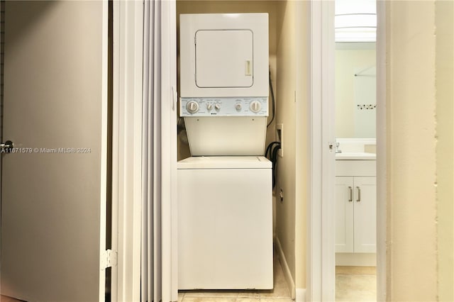 washroom with stacked washer and clothes dryer, light tile patterned flooring, and sink