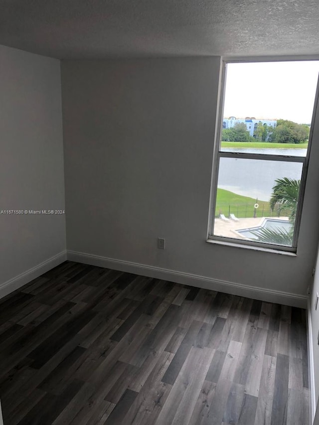 spare room featuring a textured ceiling and dark hardwood / wood-style flooring