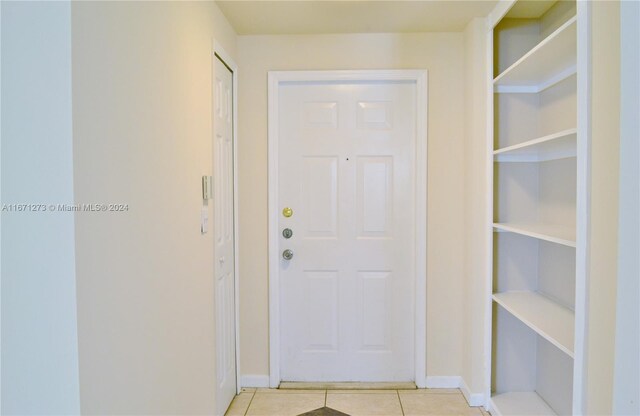 doorway with baseboards and light tile patterned floors