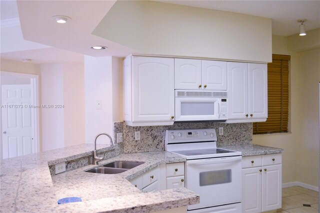 kitchen with white appliances, light stone countertops, recessed lighting, white cabinets, and a sink