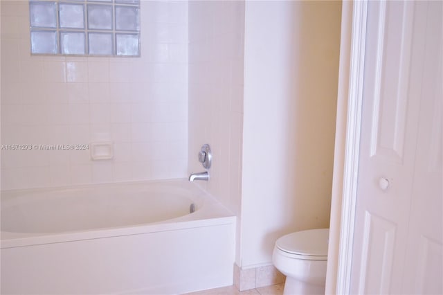 bathroom featuring tiled shower / bath, tile patterned flooring, and toilet