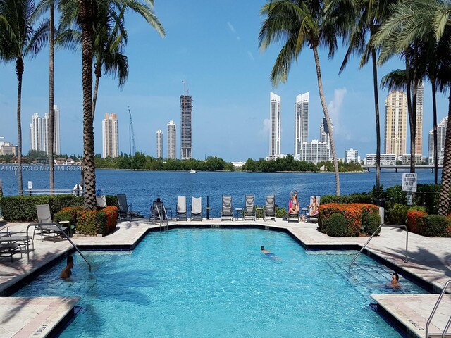 community pool featuring a view of city, a water view, and a patio area