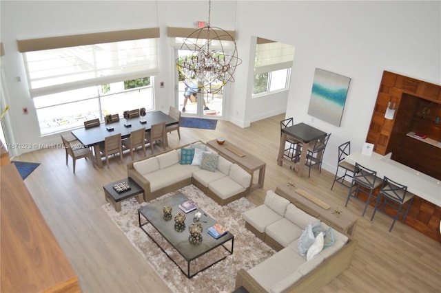 living room with a notable chandelier, a towering ceiling, hardwood / wood-style floors, and a wealth of natural light