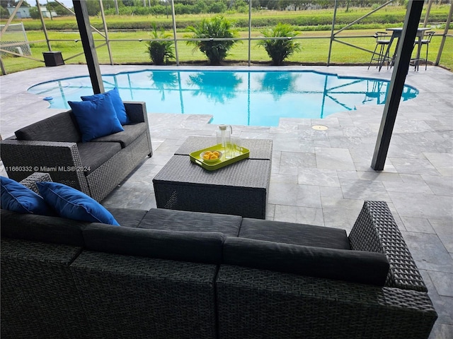 view of pool featuring outdoor lounge area, a patio, and glass enclosure