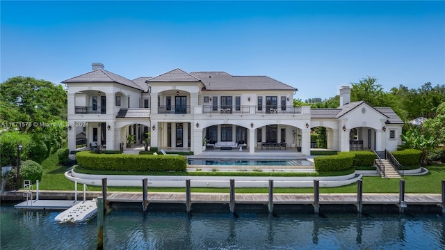 rear view of house with a balcony, a patio, and a water view