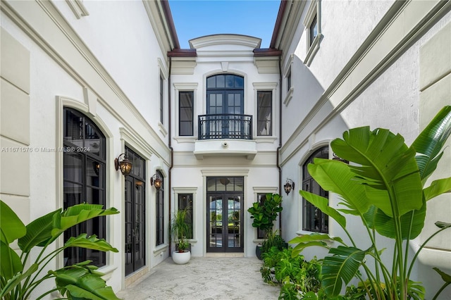 view of exterior entry featuring french doors and a balcony