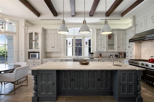 kitchen with pendant lighting, stainless steel appliances, light stone counters, and a kitchen island with sink