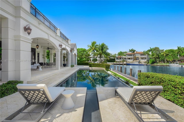 view of pool with ceiling fan, a water view, and a patio area