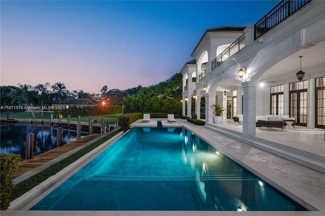 pool at dusk featuring a patio