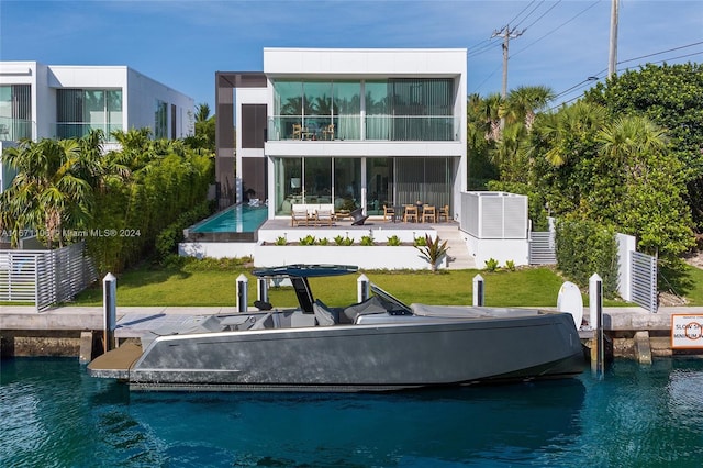 back of house with a water view, a lawn, a swimming pool, and a patio area