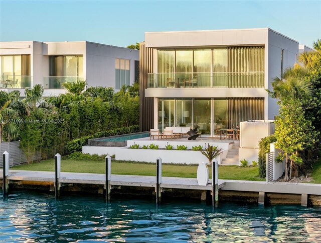 back of house featuring a water view, a lawn, and an outdoor hangout area