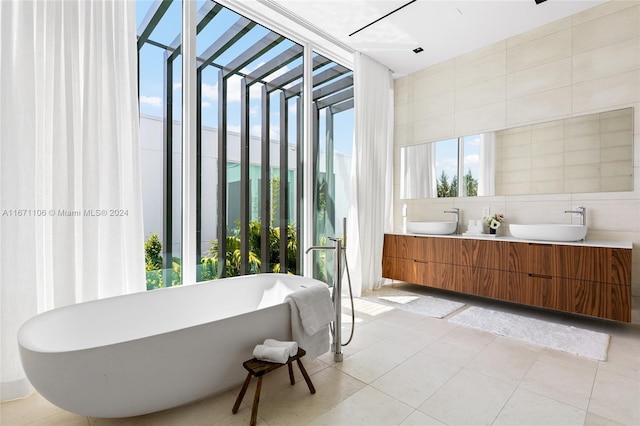 bathroom with a bathtub, vanity, tile walls, and tile patterned floors