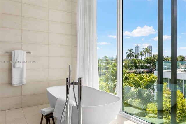 bathroom with tile walls, tile patterned flooring, and a tub to relax in