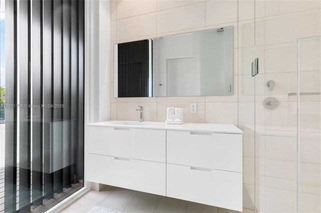 bathroom with tile patterned floors, tile walls, tasteful backsplash, an enclosed shower, and vanity