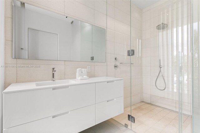 bathroom featuring tile patterned floors, tile walls, tasteful backsplash, vanity, and a shower with shower door