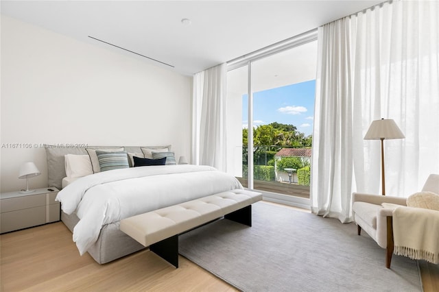 bedroom featuring a wall of windows and light hardwood / wood-style flooring