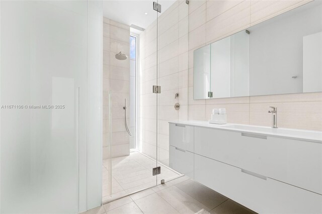 bathroom with walk in shower, vanity, tile patterned floors, and tile walls