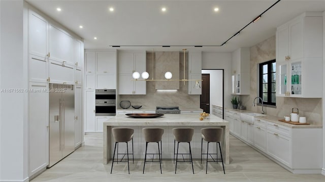 kitchen featuring pendant lighting, sink, white cabinets, a kitchen breakfast bar, and a center island