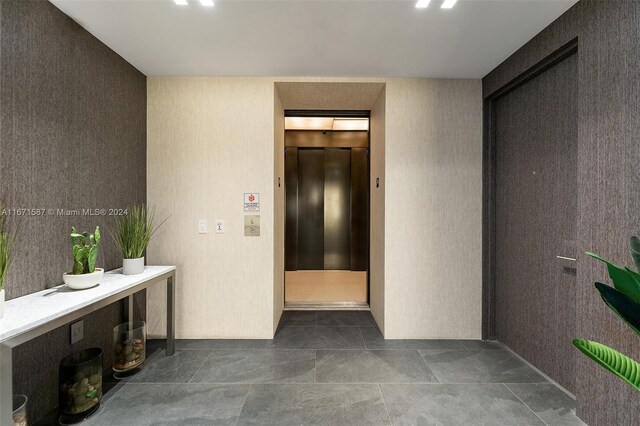 hall with elevator and tile patterned floors