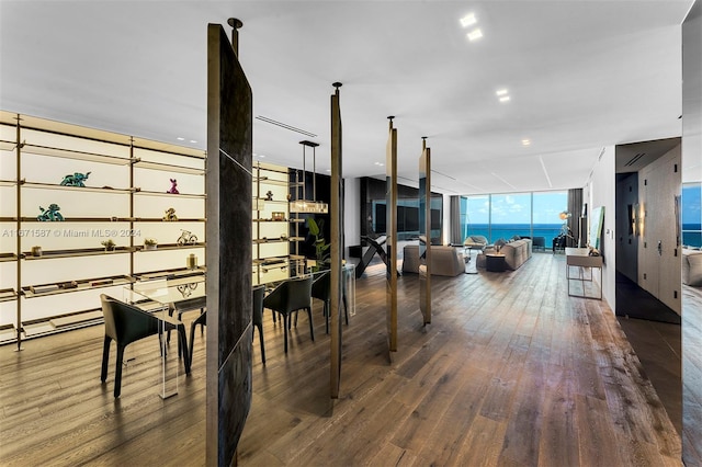 dining space featuring floor to ceiling windows, a water view, and dark hardwood / wood-style flooring