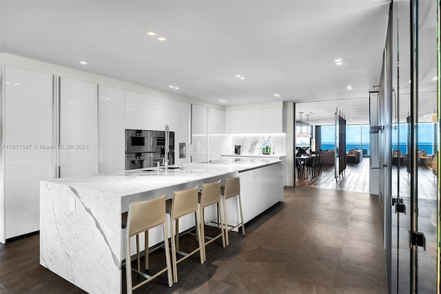 kitchen featuring stainless steel double oven, decorative backsplash, a spacious island, and white cabinets