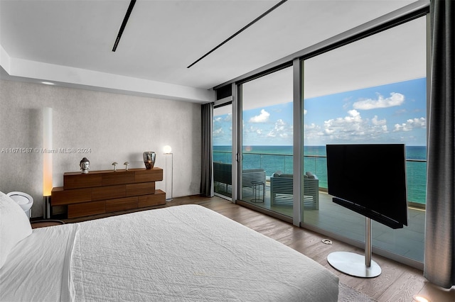 bedroom with hardwood / wood-style flooring, access to outside, and expansive windows