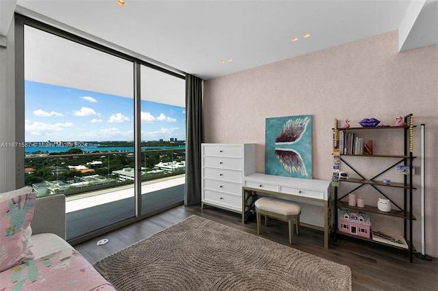 bedroom featuring a water view, a wall of windows, access to exterior, and dark hardwood / wood-style flooring