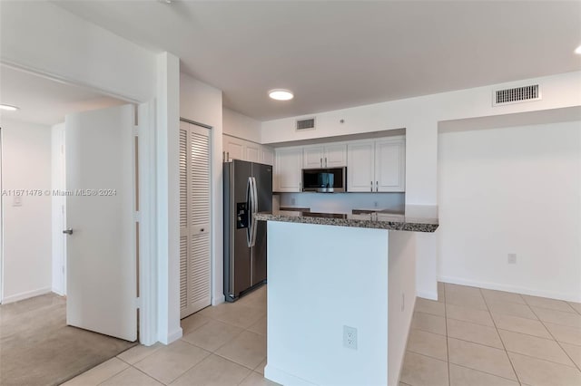 kitchen with stainless steel appliances, light colored carpet, and dark stone countertops