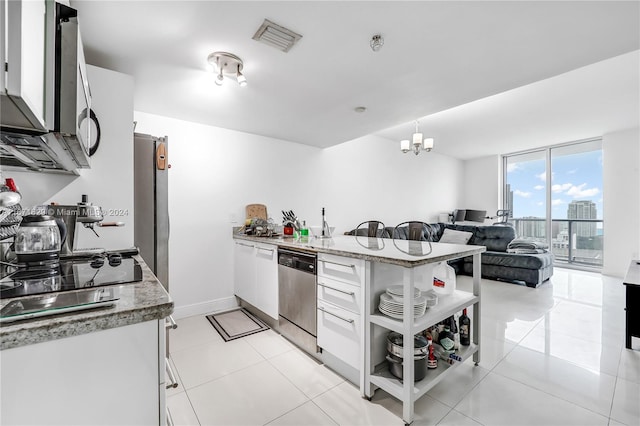 kitchen featuring light stone countertops, hanging light fixtures, white cabinetry, stainless steel dishwasher, and an inviting chandelier