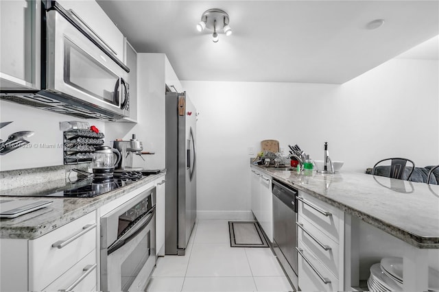 kitchen with kitchen peninsula, appliances with stainless steel finishes, white cabinetry, light tile patterned flooring, and sink