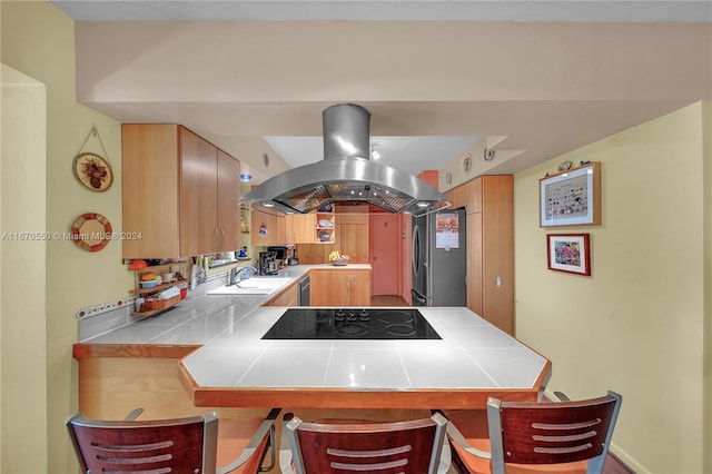 kitchen with kitchen peninsula, island range hood, sink, black appliances, and tile counters