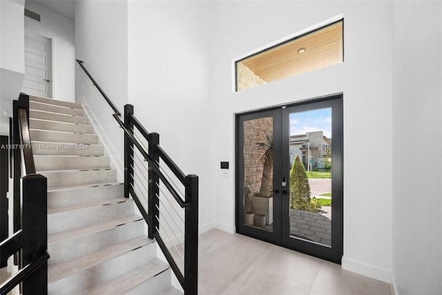 entryway featuring a towering ceiling and french doors