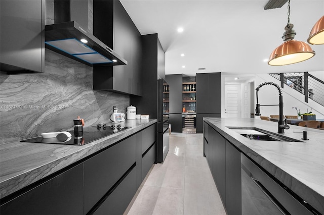 kitchen featuring wall chimney range hood, backsplash, appliances with stainless steel finishes, sink, and decorative light fixtures