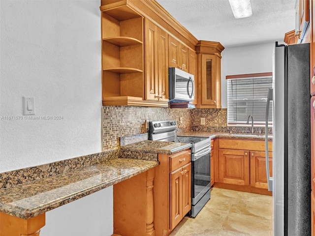 kitchen with dark stone counters, a textured ceiling, tasteful backsplash, sink, and appliances with stainless steel finishes