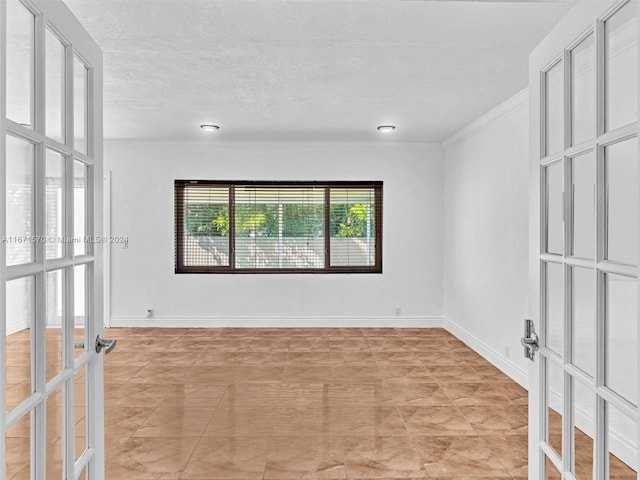 empty room featuring ornamental molding, a textured ceiling, and french doors