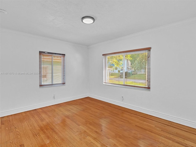 spare room with wood-type flooring, plenty of natural light, and ornamental molding