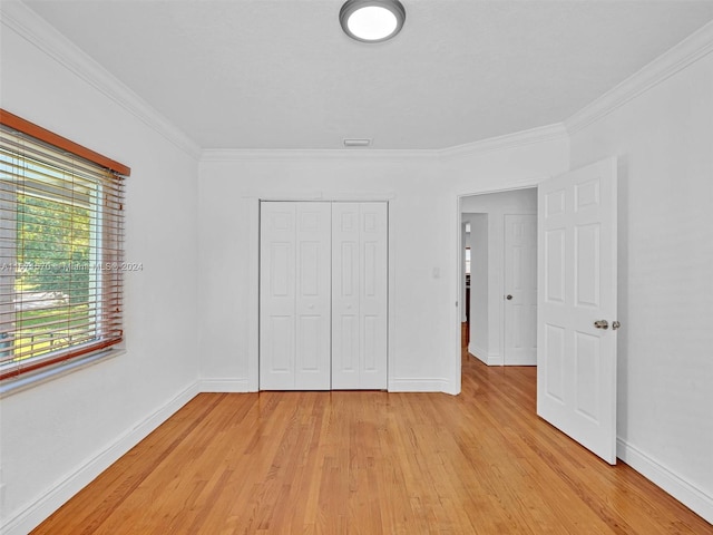 unfurnished bedroom featuring light wood-type flooring, a closet, and crown molding