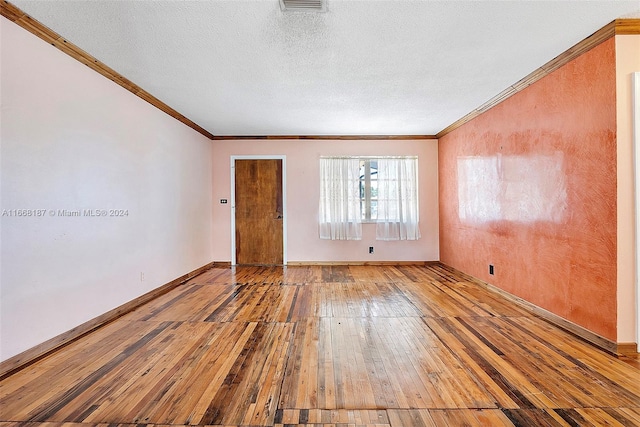 unfurnished room featuring a textured ceiling, wood-type flooring, and crown molding