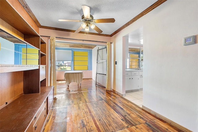 interior space with ceiling fan, a textured ceiling, light hardwood / wood-style flooring, and ornamental molding