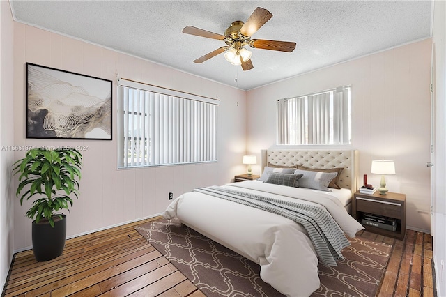 bedroom featuring ceiling fan, hardwood / wood-style flooring, multiple windows, and a textured ceiling