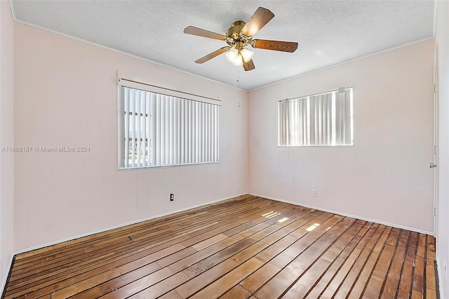 spare room with a textured ceiling, hardwood / wood-style flooring, ceiling fan, and a wealth of natural light