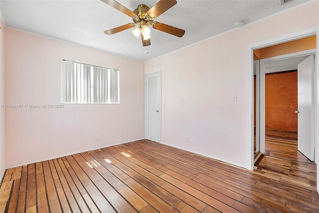 empty room with a textured ceiling, hardwood / wood-style floors, and ceiling fan