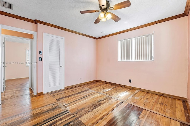 spare room with a textured ceiling, crown molding, hardwood / wood-style floors, and ceiling fan