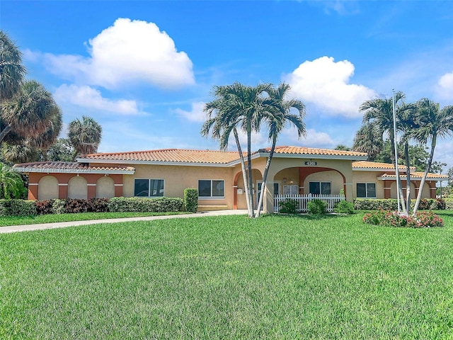 4701 Mainland Dr, Tamarac, FL 33319 - mediterranean / spanish house featuring a front lawn, a tiled roof, and stucco siding