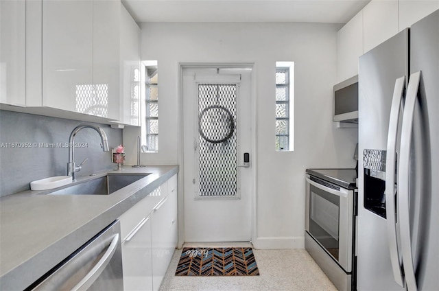 kitchen featuring stainless steel appliances, plenty of natural light, white cabinets, and sink