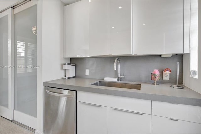 kitchen featuring tasteful backsplash, sink, stainless steel dishwasher, and white cabinets