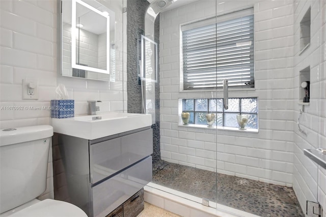 bathroom featuring toilet, tasteful backsplash, vanity, tile walls, and tiled shower