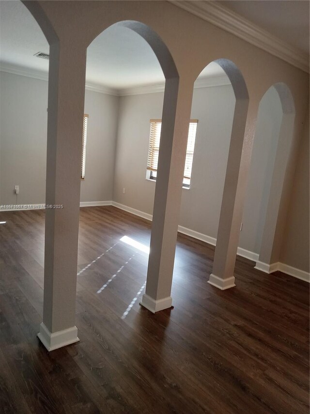 empty room featuring dark wood-type flooring and ornamental molding