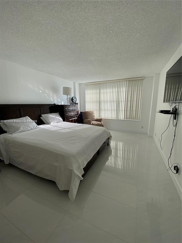 tiled bedroom featuring baseboards and a textured ceiling