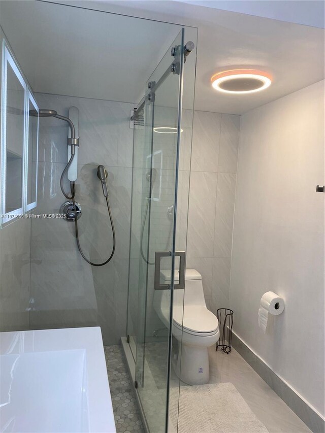 bathroom featuring tile patterned flooring, a shower with door, and toilet